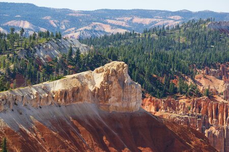 A landscape shot with a red mine in the foreground and a forest of green trees lining the background.
