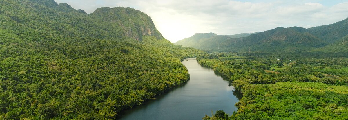 river in southeast Asia with green forest and mountains in background